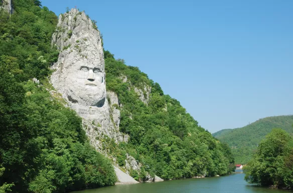 A large rock sculpture of decebalus overlooking the Danube River gorge